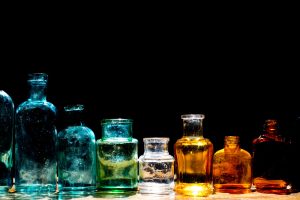 Colorful,Small,Glass,Bottles,In,Sunlight,On,Black,Background.,Reflected